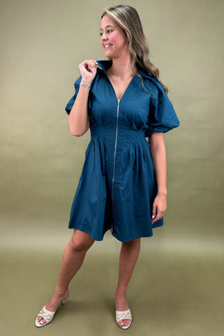 Woman wearing a blue dress against a green background