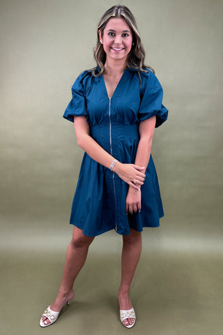 Woman wearing a blue dress against a green background