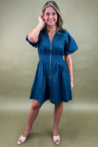 Woman wearing a blue dress against a green background