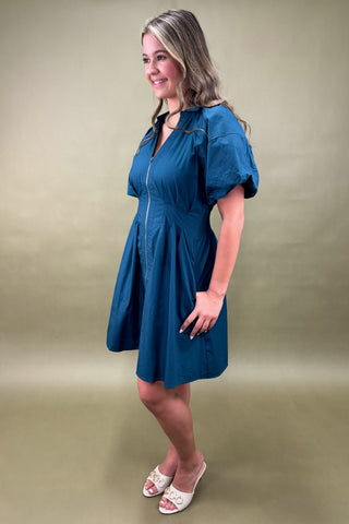 Woman wearing a blue dress against a green background