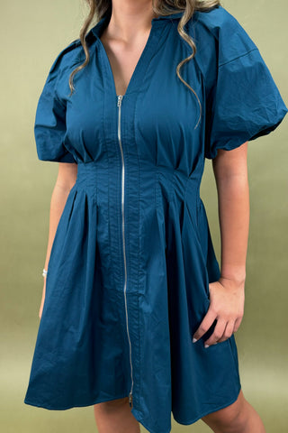 Woman wearing a blue dress against a green background