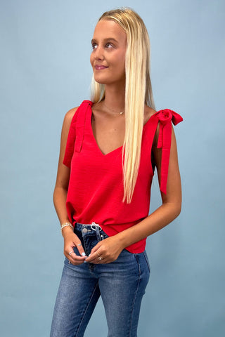 Woman wearing a red top with bow straps against a light blue background
