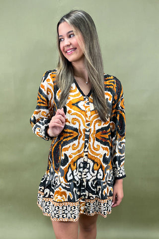 Woman wearing a patterned dress against a plain background