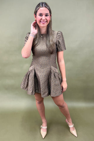 Woman wearing a gold dress against a green background