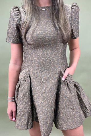 Woman wearing a patterned dress with puff sleeves against a plain background