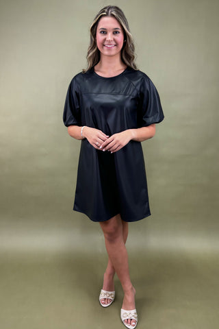 Woman wearing a black dress against a green background