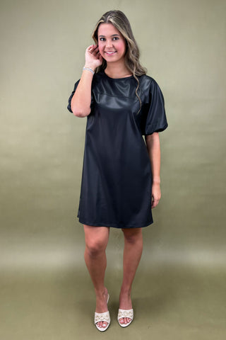 Woman wearing a black dress against a green background