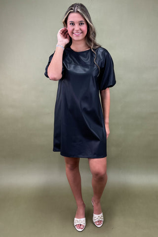 Woman wearing a black dress against a green background