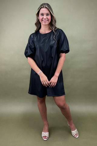 Woman wearing a black dress against a green background