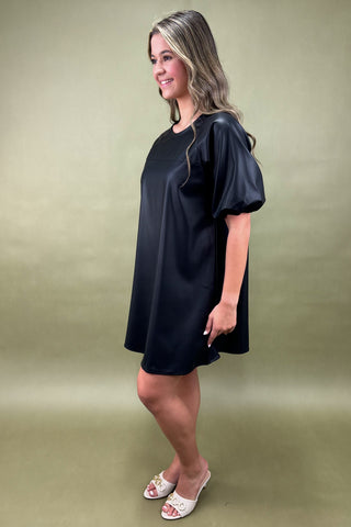 Woman wearing a black dress against a green background