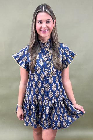Woman wearing a blue floral dress against a plain background