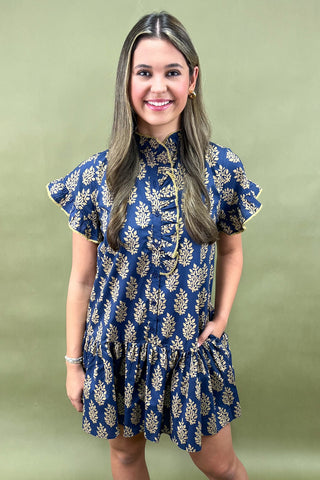 Navy blue mini dress with gold leaf print, ruffled sleeves, high neckline with button details, and tiered hem for an elegant fall look