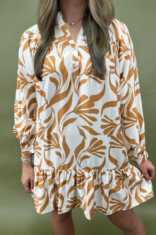 Woman wearing a floral dress with long sleeves against a green background