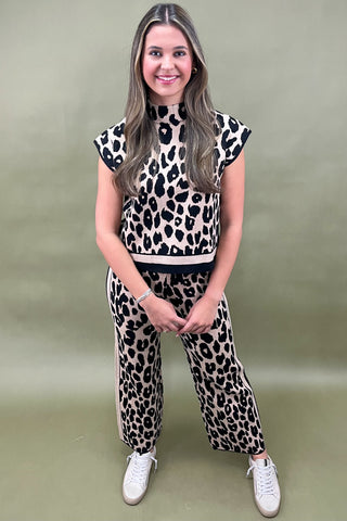 Pair of beige quilted slides on a wooden surface with a plant in the background