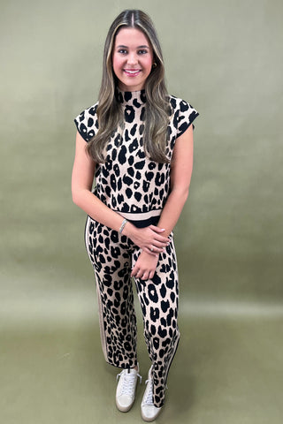Woman wearing a leopard print outfit against a plain background