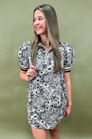 Woman wearing a black and white floral dress against a green background