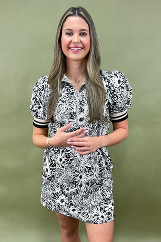Woman wearing a black and white floral dress against a green background