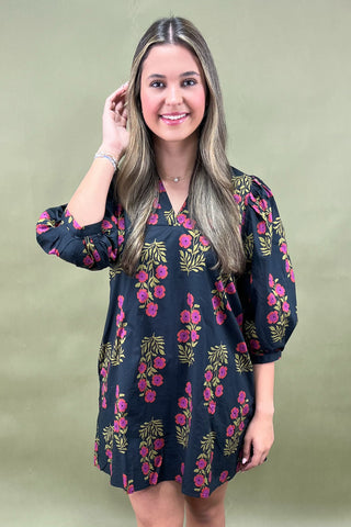 Woman wearing a navy floral dress against a green background