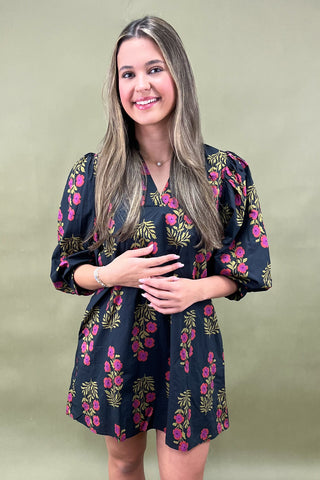 Woman wearing a floral dress against a plain background