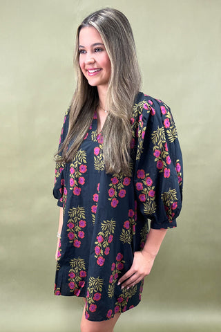 Woman wearing a floral dress against a plain background