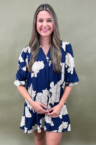 Woman wearing a blue floral dress against a plain background