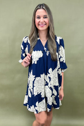 Woman wearing a navy floral dress against a green background