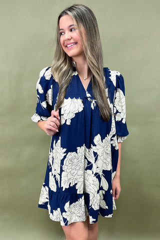 Woman wearing a blue floral dress against a green background