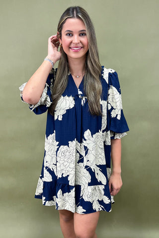 Woman wearing a navy floral dress against a green background