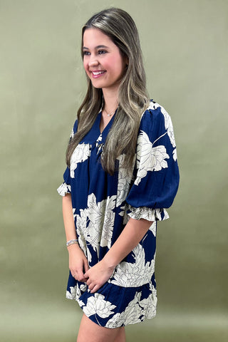 Woman wearing a blue floral dress against a green background