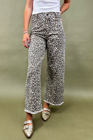 Person wearing leopard print pants on a plain background
