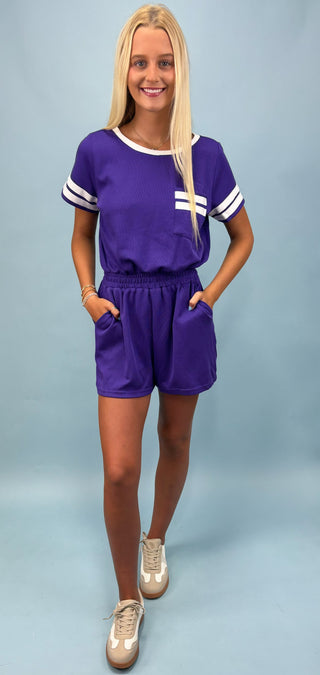 Woman wearing a purple outfit with white accents on a light blue background