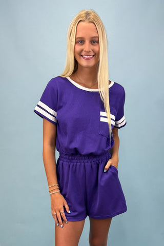 Woman wearing a purple outfit with white accents on a light blue background
