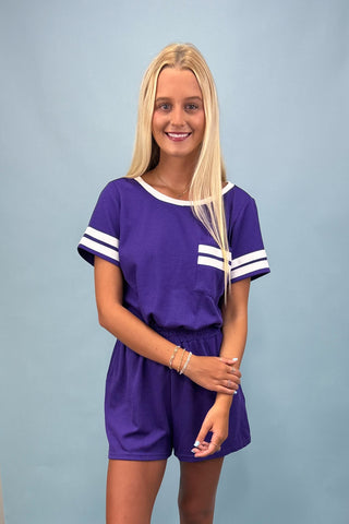 Woman wearing a purple outfit with white stripes on a plain background