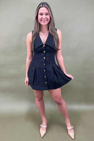 Woman wearing a black dress with buttons on a beige background