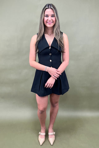 Woman wearing a black sleeveless dress against a plain background