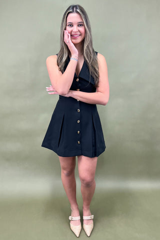 Woman wearing a black dress with buttons on a green background