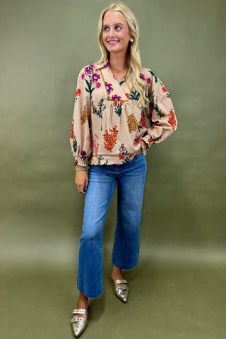 Woman wearing a floral blouse and blue jeans against a green background