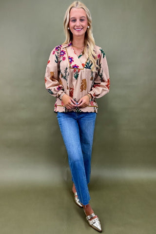 Woman wearing a patterned blouse and blue jeans against a green background