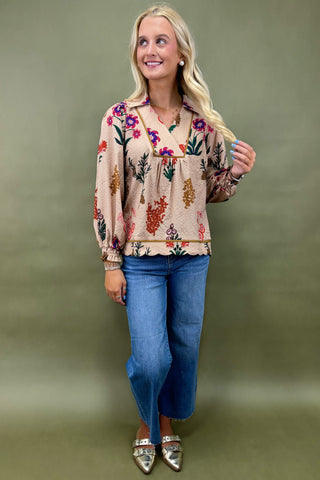 Woman wearing a floral blouse and blue jeans against a green background