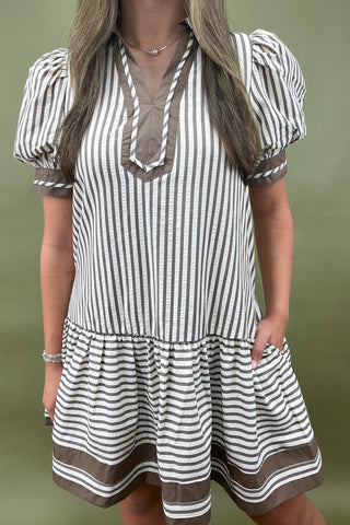 Woman wearing a striped dress with short sleeves against a green background
