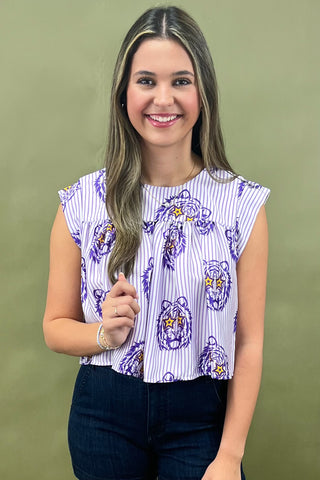 Woman wearing a patterned top and jeans against a green background
