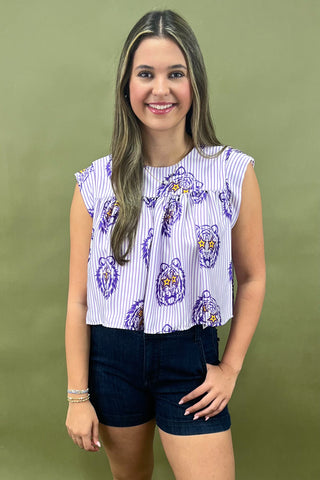 Woman wearing a patterned top and jeans against a green background