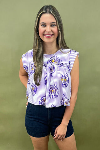 Woman wearing a patterned top and jeans against a green background