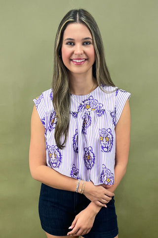 Woman wearing a patterned top and black shorts against a green background
