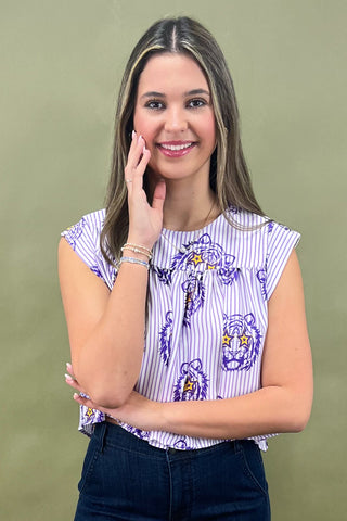 Woman wearing a patterned top and jeans against a green background