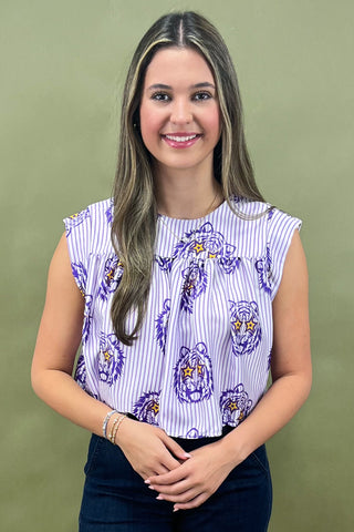 Woman wearing a patterned top and jeans against a green background