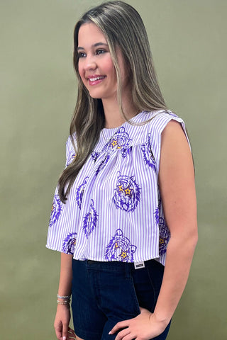Woman wearing a sleeveless top with purple designs against a green background