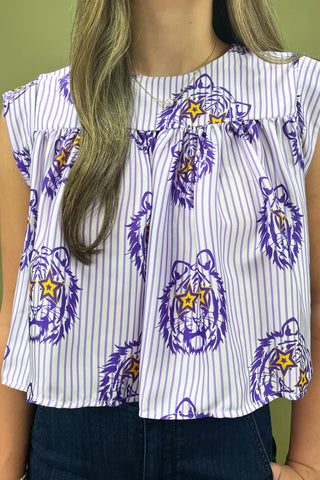 Woman wearing a patterned top and jeans against a green background