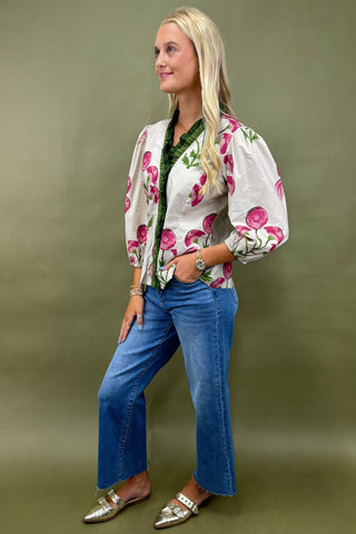 Woman wearing a floral cardigan and blue jeans on a green background
