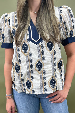 Cream and navy puff sleeve blouse with geometric print styled with light wash wide leg jeans and white sneakers.